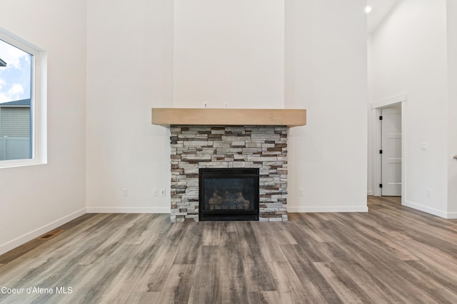 6696 Portrush Dr, Rathdrum, ID 83858 - unfurnished living room featuring a high ceiling, a fireplace, baseboards, wood finished floors, and visible vents