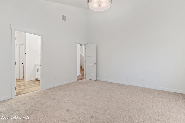 6696 Portrush Dr, Rathdrum, ID 83858 - unfurnished bedroom featuring visible vents, a towering ceiling, baseboards, connected bathroom, and carpet