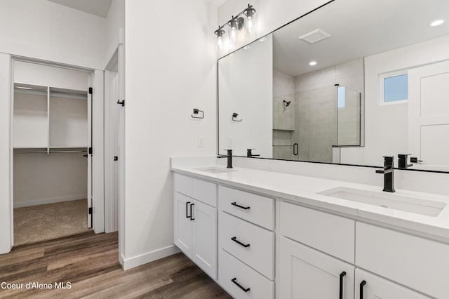 6696 Portrush Dr, Rathdrum, ID 83858 - bathroom featuring a spacious closet, a shower stall, a sink, and wood finished floors