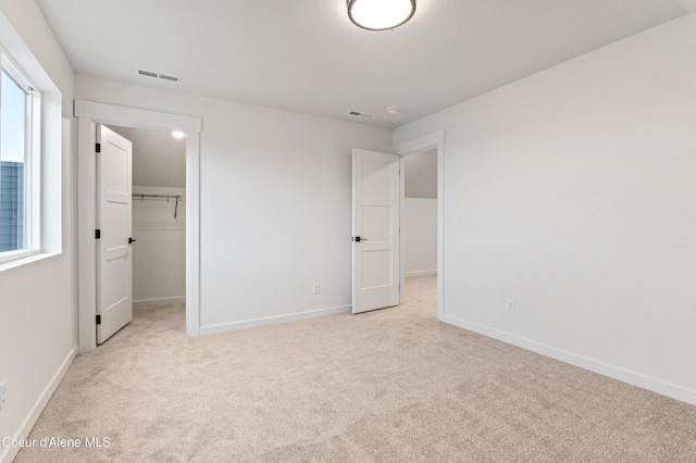 6696 Portrush Dr, Rathdrum, ID 83858 - unfurnished bedroom featuring carpet flooring, baseboards, visible vents, and a walk in closet