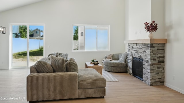6696 Portrush Dr, Rathdrum, ID 83858 - living area featuring a stone fireplace, light wood finished floors, high vaulted ceiling, and baseboards