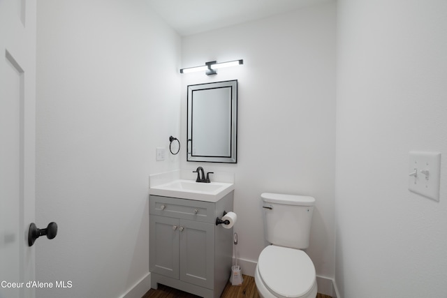 7435 N Cornwall St, Coeur Dalene, ID 83815 - half bathroom featuring vanity, toilet, baseboards, and wood finished floors