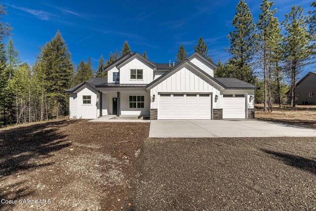 7587 E Duke Ln, Athol, ID 83801 - modern farmhouse style home with an attached garage, stone siding, board and batten siding, a porch, and concrete driveway
