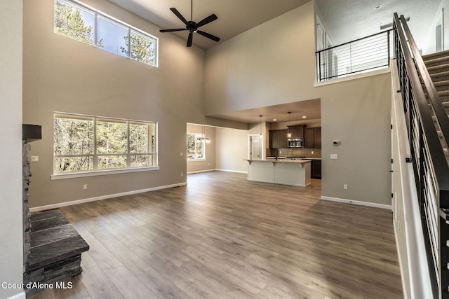 7587 E Duke Ln, Athol, ID 83801 - unfurnished living room featuring wood finished floors, baseboards, ceiling fan, and a high ceiling