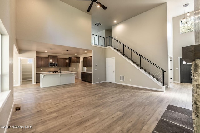 7587 E Duke Ln, Athol, ID 83801 - unfurnished living room with visible vents, light wood-style floors, ceiling fan, and a high ceiling