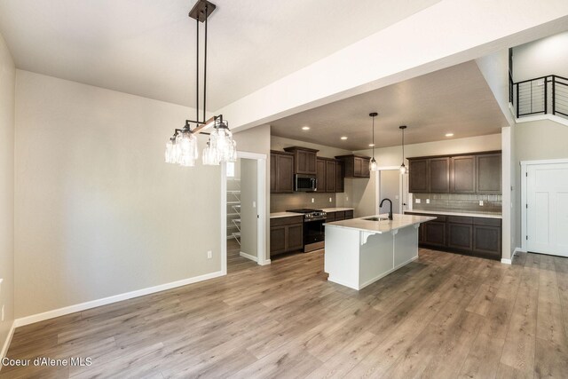 7587 E Duke Ln, Athol, ID 83801 - kitchen featuring dark brown cabinets, an island with sink, a sink, appliances with stainless steel finishes, and backsplash