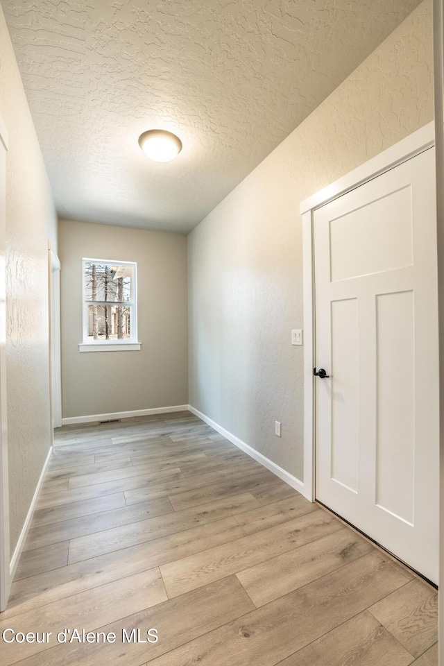 7587 E Duke Ln, Athol, ID 83801 - empty room with light wood-style floors, baseboards, a textured wall, and a textured ceiling