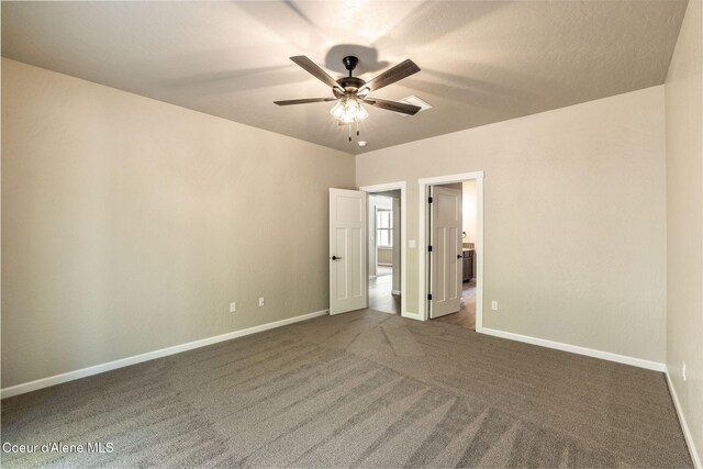 7587 E Duke Ln, Athol, ID 83801 - unfurnished bedroom with a ceiling fan, baseboards, ensuite bath, and dark colored carpet