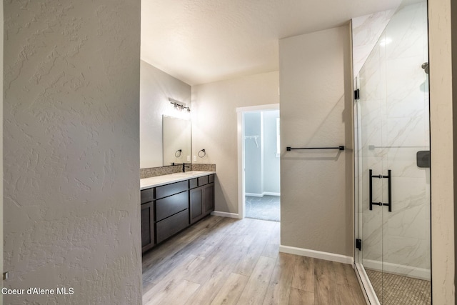 7587 E Duke Ln, Athol, ID 83801 - full bath featuring wood finished floors, baseboards, vanity, a marble finish shower, and a textured wall