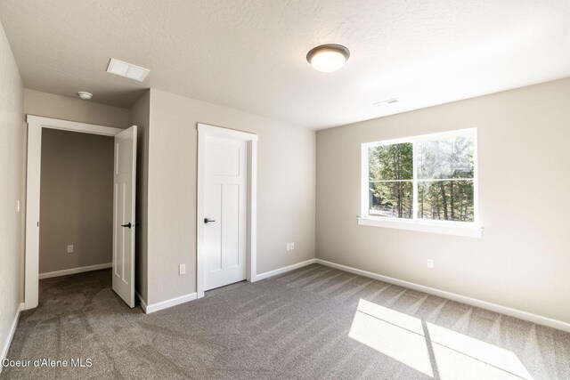 7587 E Duke Ln, Athol, ID 83801 - unfurnished bedroom with carpet floors, a textured ceiling, baseboards, and visible vents