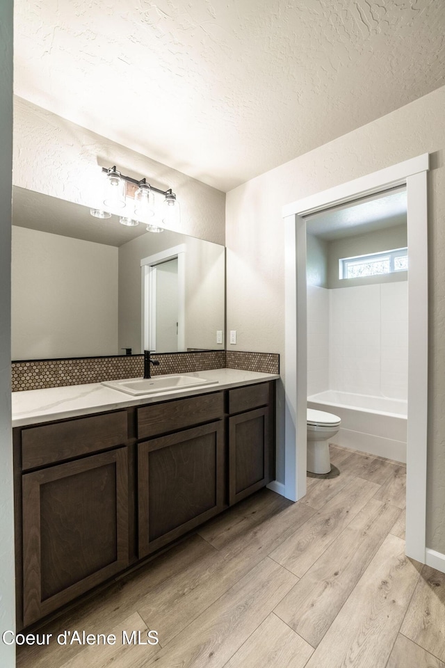 7587 E Duke Ln, Athol, ID 83801 - full bath featuring vanity, wood finished floors, toilet, a tub, and a textured ceiling