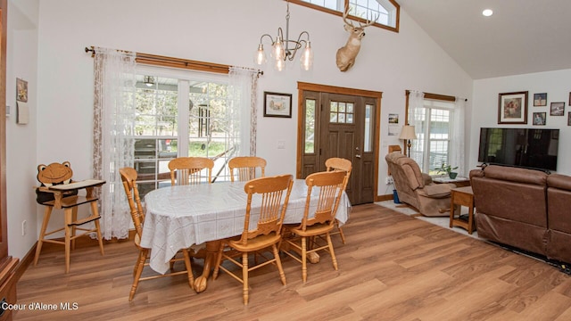 dining space with light wood-type flooring, recessed lighting, a notable chandelier, and high vaulted ceiling
