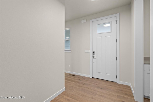 foyer featuring baseboards, light wood-style flooring, and visible vents