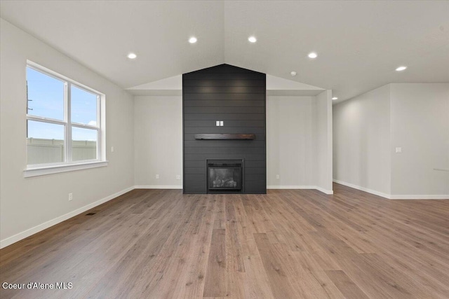 unfurnished living room featuring a fireplace, wood finished floors, baseboards, lofted ceiling, and recessed lighting
