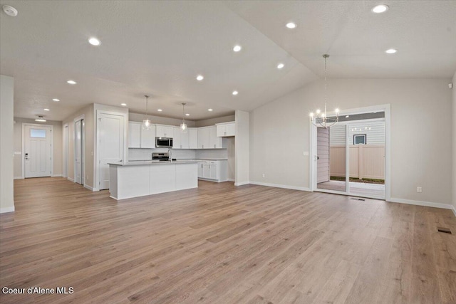 unfurnished living room with baseboards, recessed lighting, a notable chandelier, and light wood-type flooring