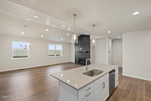 kitchen with a kitchen island with sink, a large fireplace, a sink, dark wood-style floors, and lofted ceiling