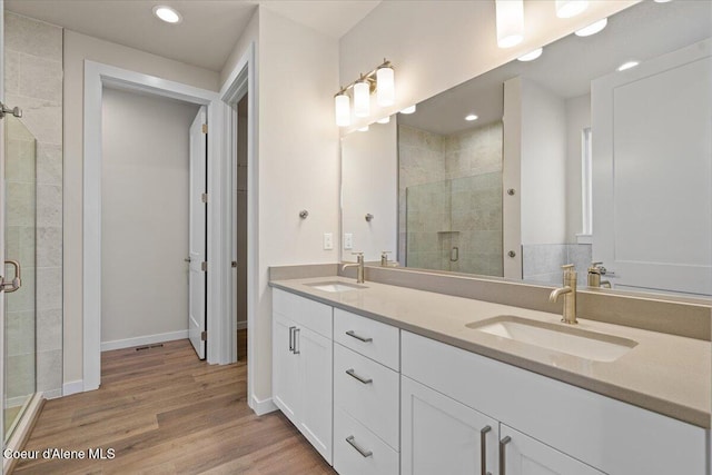 bathroom with recessed lighting, a shower stall, a sink, and wood finished floors