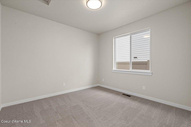carpeted empty room with visible vents, a textured ceiling, and baseboards
