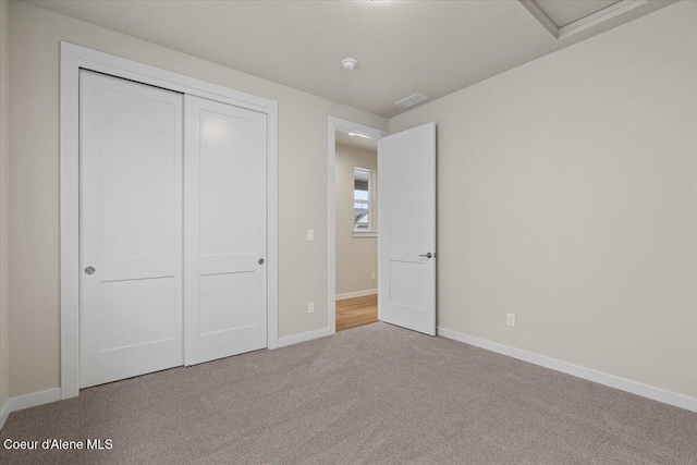 unfurnished bedroom featuring carpet floors, baseboards, visible vents, and a closet