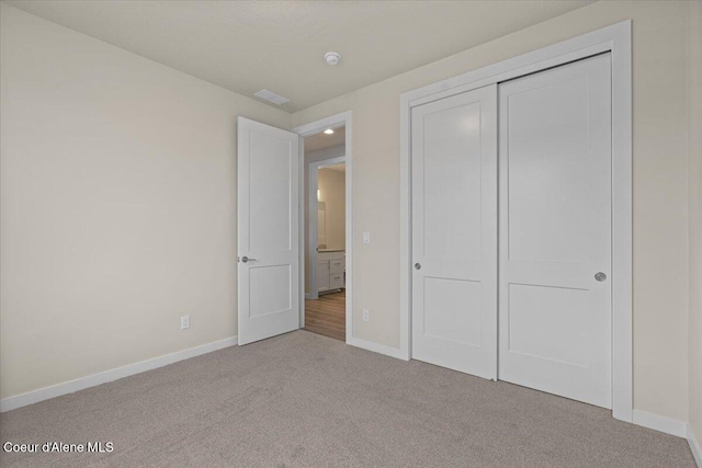 unfurnished bedroom featuring baseboards, visible vents, carpet, and a closet