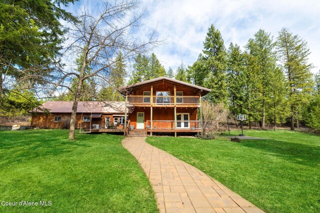 rear view of house with a lawn, a wooden deck, and french doors