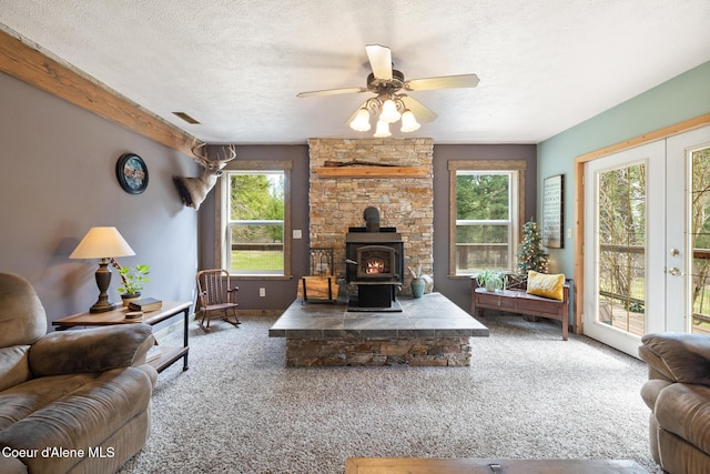 living room with a wood stove, a textured ceiling, and carpet flooring