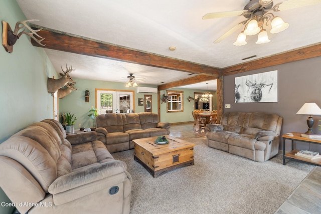 living room with visible vents, beamed ceiling, a wall mounted AC, and ceiling fan with notable chandelier