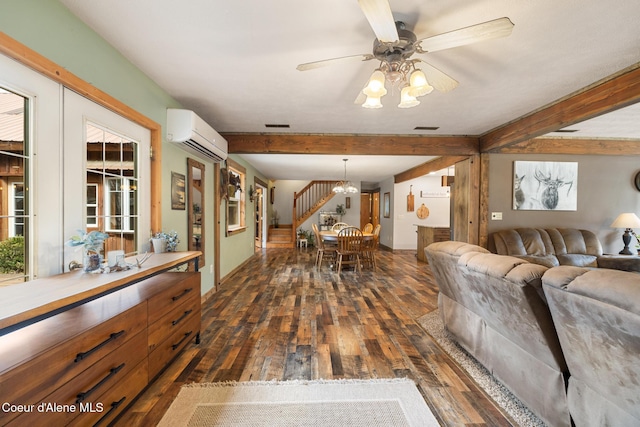 living room with a wall unit AC, dark wood finished floors, beamed ceiling, ceiling fan with notable chandelier, and stairs