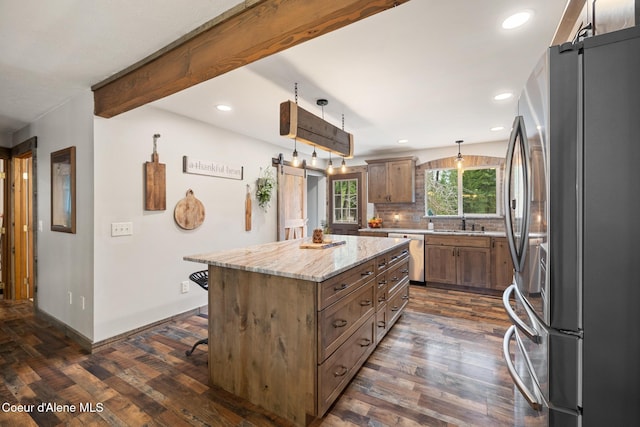 kitchen with dark wood-style floors, a center island, a sink, appliances with stainless steel finishes, and backsplash