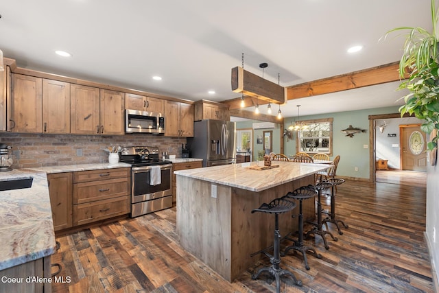 kitchen featuring decorative backsplash, a breakfast bar area, stainless steel appliances, and dark wood-type flooring