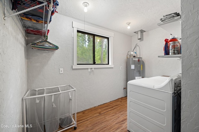 laundry room with laundry area, a textured ceiling, water heater, washer / dryer, and wood finished floors