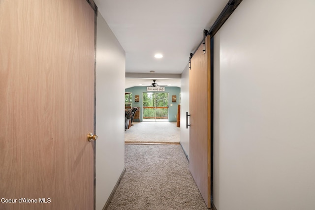 corridor with carpet flooring, recessed lighting, baseboards, and a barn door