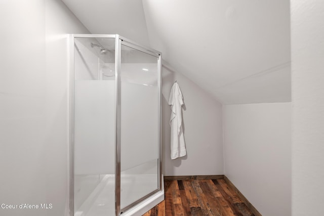 bathroom featuring vaulted ceiling, wood finished floors, and a stall shower