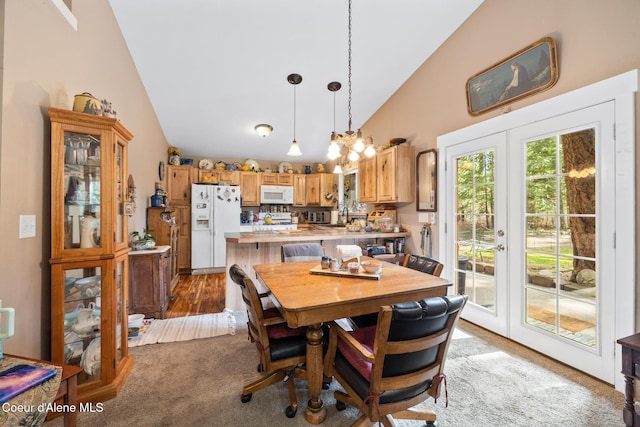 carpeted dining space featuring a sink, high vaulted ceiling, and french doors