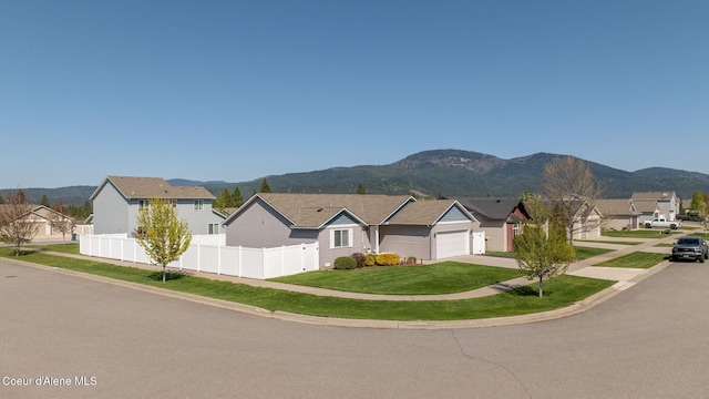 single story home with a residential view, fence, a garage, a mountain view, and driveway