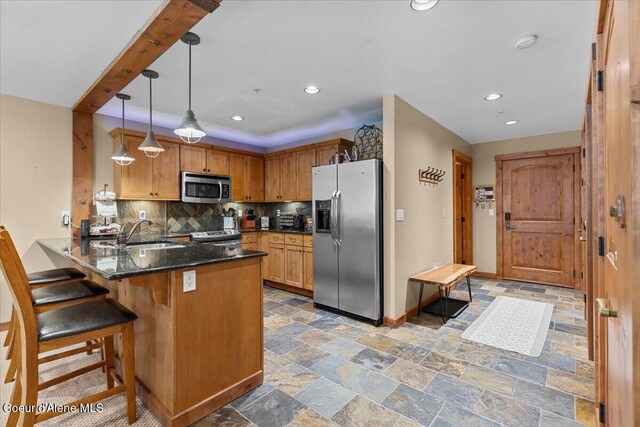 834 Mckinley Ave Unit 208, Kellogg, ID 83837 - kitchen featuring appliances with stainless steel finishes, a sink, a peninsula, backsplash, and light stone finish floors