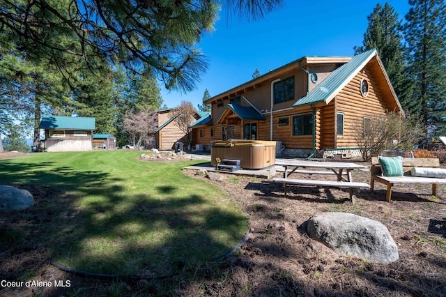 rear view of property featuring a lawn, a hot tub, log exterior, and metal roof