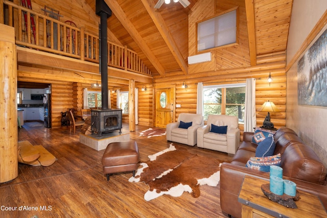 living area with wooden ceiling, a wood stove, high vaulted ceiling, and rustic walls