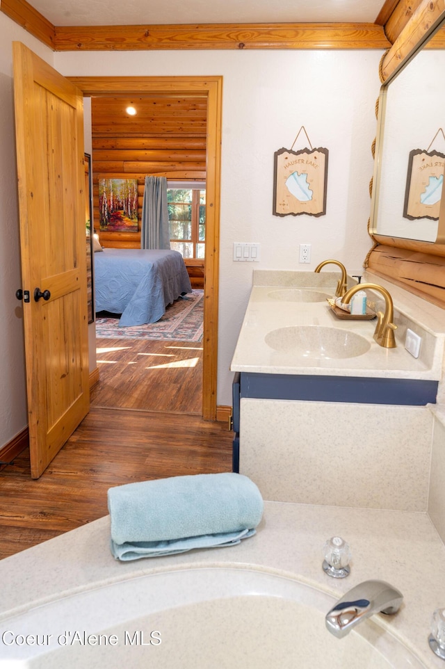 bathroom featuring connected bathroom, baseboards, wood finished floors, and vanity