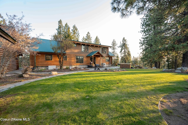 view of front facade with a front yard, a patio area, metal roof, and log siding