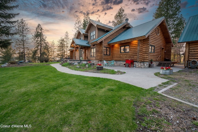 back of property at dusk featuring a lawn, a patio area, log siding, and metal roof