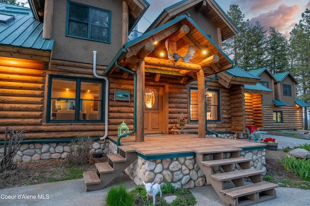 exterior space with metal roof, covered porch, and log siding
