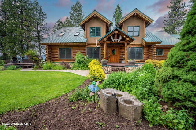 cabin with metal roof, log exterior, and a lawn