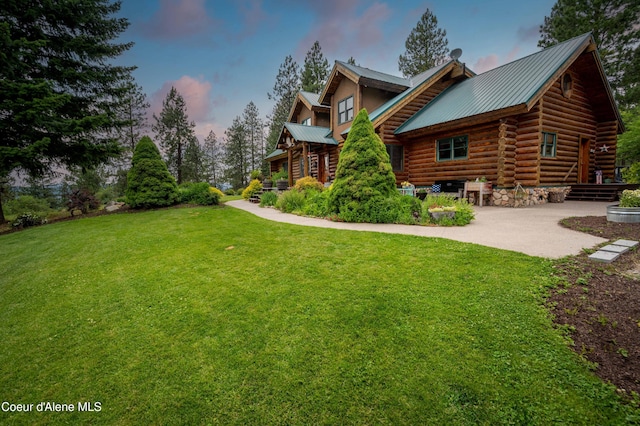 property exterior at dusk with metal roof, a patio, a yard, and log exterior