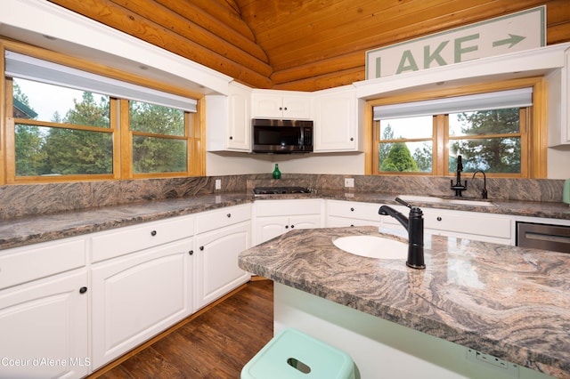 kitchen featuring lofted ceiling, dark wood finished floors, a sink, stainless steel appliances, and white cabinets