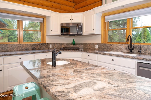 kitchen with a sink, white cabinetry, dark stone countertops, and appliances with stainless steel finishes