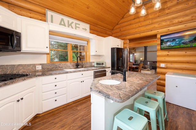 kitchen with a sink, appliances with stainless steel finishes, log walls, wooden ceiling, and vaulted ceiling