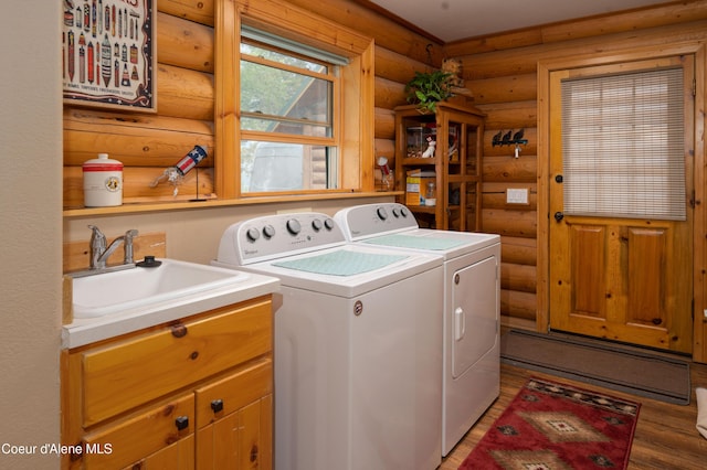laundry room with a sink, light wood-style flooring, independent washer and dryer, and log walls
