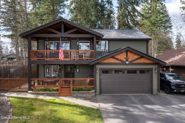 view of front of house featuring metal roof, a garage, fence, a balcony, and aphalt driveway