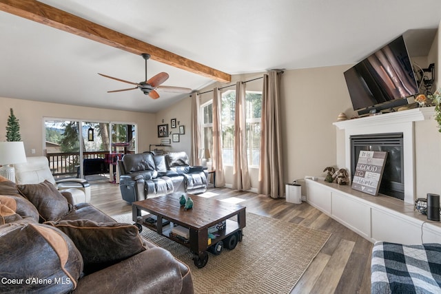 living room featuring a fireplace with raised hearth, a ceiling fan, lofted ceiling with beams, and wood finished floors